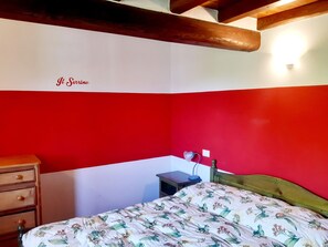 Un dormitorio con cama, mesita de noche, cómoda y una pared con texto parcial.