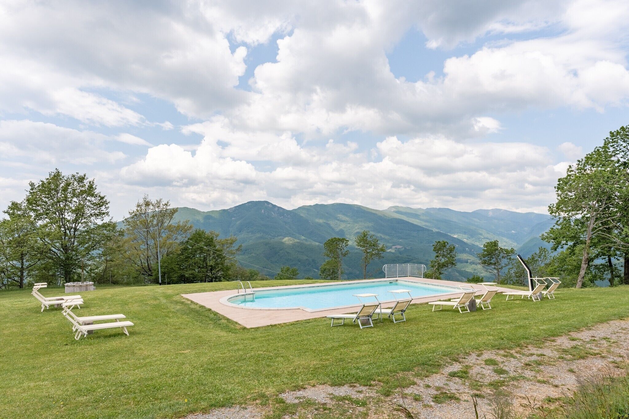A pool with lounge chairs and a view of mountains.