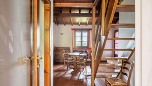 Una escalera de madera que lleva a un comedor con una mesa y sillas.