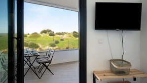 Un balcón con una mesa y sillas, un televisor montado en la pared y una cesta en un estante.