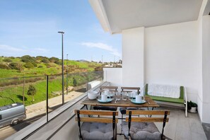 A balcony with a table set for dining, chairs, and a view of the countryside.