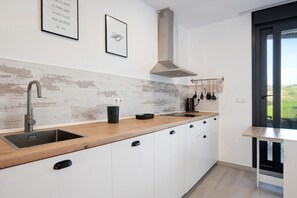 A modern kitchen with a wooden countertop, stainless steel sink, and a view of the outdoors.