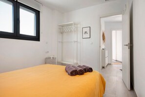 A bedroom with a bed, a window, a wardrobe, and a framed picture on the wall.