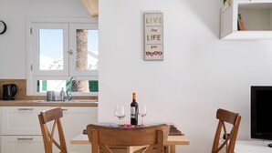 Una cocina con una mesa de comedor, sillas, una botella de vino y copas.