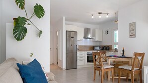 Una cocina moderna con refrigerador, microondas y estufa. Hay una mesa de comedor con sillas y un sofá con cojines.