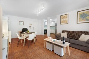 Moderni olohuone, jossa on ruokailutila, sohva ja taustalla keittiö.