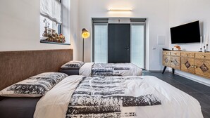 Ein Schlafzimmer mit zwei Betten, einem Fernseher, einer Kommode und einem Fenster mit Blick.