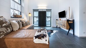 Ein modernes Wohnzimmer mit einer Couch, einem Flachbildfernseher, einem Holzschrank und einem großen Fenster mit Blick.