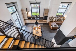A modern kitchen with a dining area, large windows, and a staircase. - Loft "Casa Facco" with Mountain View, Garden & Wi-Fi (Bocenago)