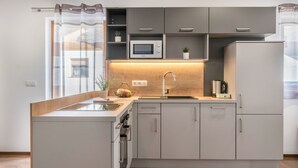 A modern kitchen with a built-in microwave, a sink, and a refrigerator. - Apartment "Trojer 2" with Mountain View, Whirlpool & Wi-Fi (Sarentino)