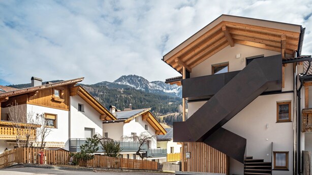 A residential building with a wooden staircase, a mountain backdrop, and a clear sky. - Apartment "Trojer 2" with Mountain View, Whirlpool & Wi-Fi (Sarentino)