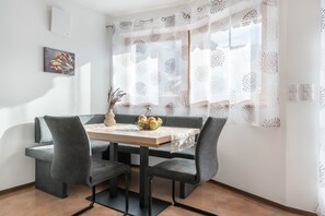 Un coin repas comprenant une table, des chaises et une fenêtre agrémentée de rideaux à motifs.