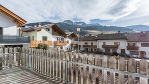 Zona residencial con valla de madera, casas con balcones y montañas al fondo.
