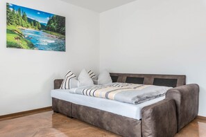 Une pièce avec un lit, un tableau représentant une rivière et un sol carrelé.