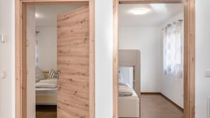 Una habitación con una litera, una puerta de madera y una pared blanca con cortina.
