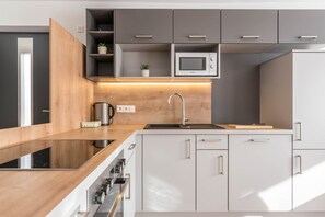 Une cuisine moderne dotée d’un plan de travail en bois, d’appareils électroménagers en acier inoxydable et de meubles de couleur grise.