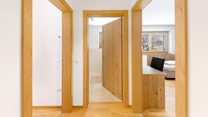 Ein Flur mit Holztüren, die zu einem Raum mit Schreibtisch und Stuhl führen.