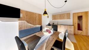 Eine moderne Küche mit Holzschränken, einem Esstisch mit Stühlen und einer hängenden Pendelleuchte.