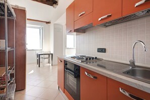A kitchen with orange cabinets, a stainless steel sink, and a built-in oven.