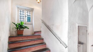 Un escalier orné d’un pot de fleurs, une fenêtre à carreaux et une porte portant l’inscription « GAZ ».