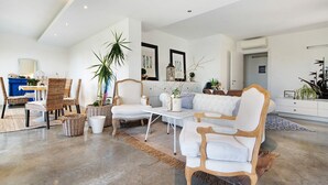 A spacious living area with a high ceiling, wicker furniture, and a large potted plant.