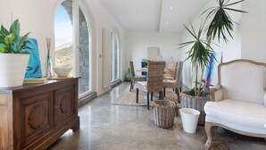 A spacious room with a dining area, a sofa, and potted plants.