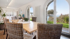 A dining area with a large table, wicker chairs, and a view of the outdoors.