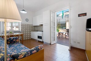 A compact living space with a kitchenette, a dining area, and a bedroom with a bed and a lamp.