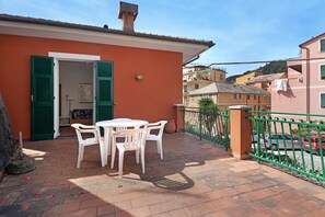 A terrace with a table and chairs, a door with green shutters, and a view of neighboring buildings. - Apartment "Via Colombo 12 Bilo" with Terrace (Bonassola)