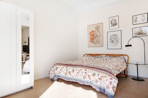 Un dormitorio con cama, armario y una obra de arte en la pared.