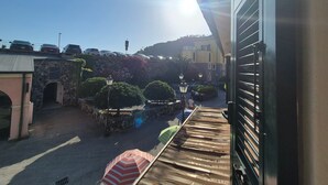 Ein Balkon mit Blick auf eine Straße, parkende Autos und ein Gebäude mit einer Steinfassade.