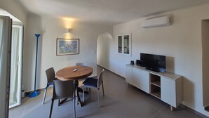 Ein gemütlicher Wohnbereich mit Essplatz, einem Flachbildfernseher und einem Bild an der Wand.