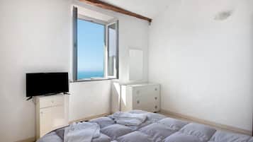 Ein Schlafzimmer mit Bett, Fernseher, Kommode und Fenster mit Ausblick.