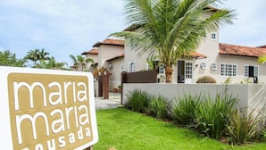 A sign for 'Maria Maria Pousada' with a well-maintained lawn and a palm tree in the foreground. - Pousada Maria Maria Buzios (Búzios)