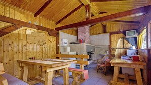 A wooden cabin interior with a dining table, benches, a kitchen area, and a television. - Andrea in Sertić Poljana  - Haus für 6 Personen (Plitvička jezera)