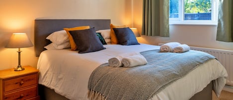 A neatly made bed with a patterned bedspread, a bedside lamp, and a wall-mounted artwork.