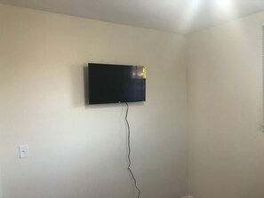 Une pièce avec un téléviseur fixé au mur, une prise de courant et un câble reliant le téléviseur à la prise.