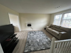 A living room with a flat-screen TV, a beige sofa, a patterned rug, and a fireplace. - Cozy and peaceful place to unwind and relax! (Gallatin)