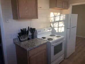 A kitchen with a stove, refrigerator, and wooden cabinets.