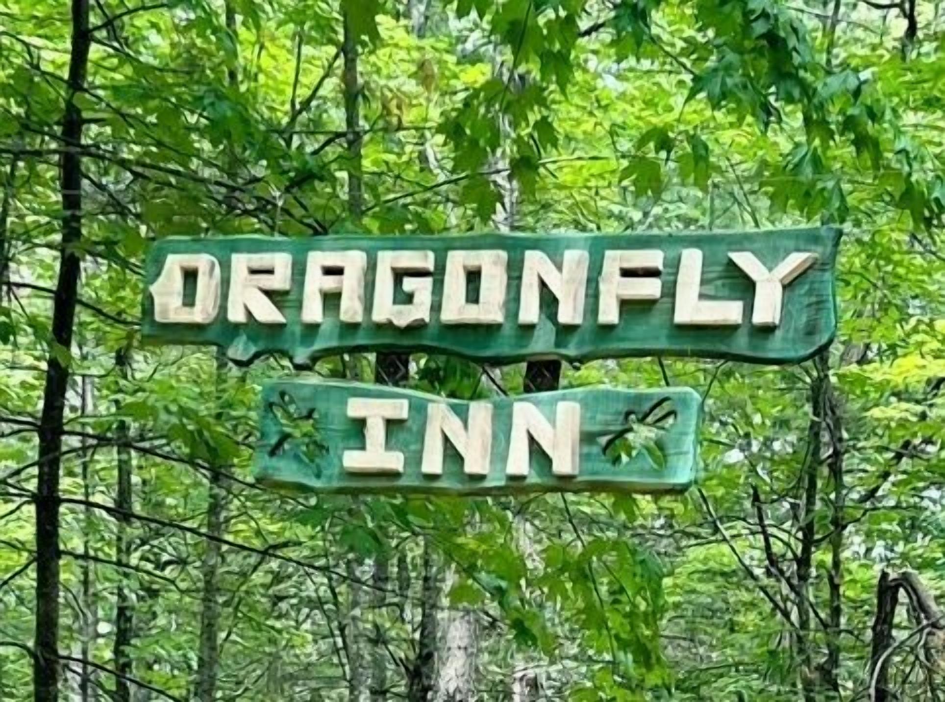 A wooden sign with the text "Dragonfly Inn" surrounded by trees.