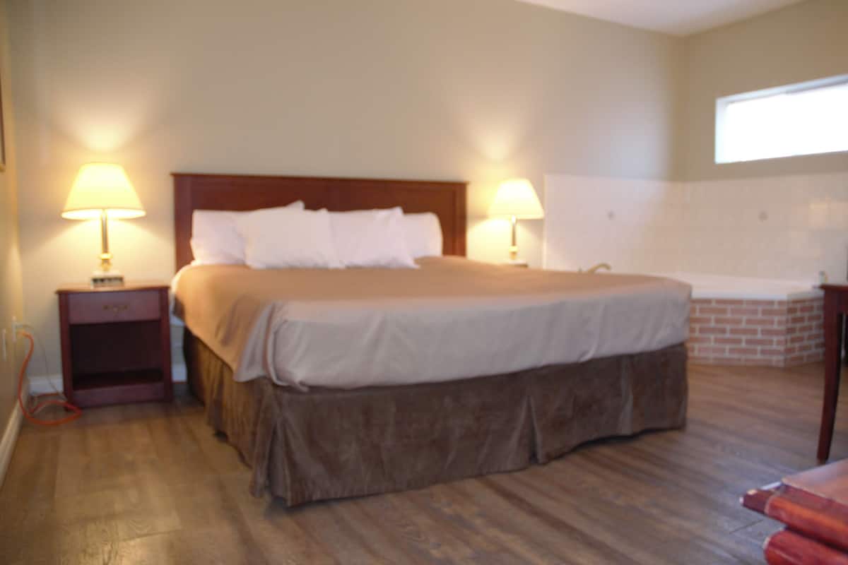 A neatly made bed with a wooden headboard, two bedside lamps, and a small nightstand.