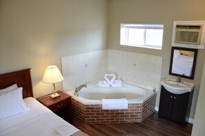 Ein Hotelzimmer mit einer großen Badewanne, einer Nachttischlampe, einem Fenster und einem Waschbecken.