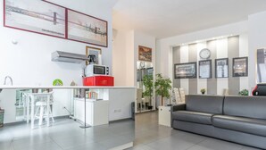 A modern kitchen with white cabinetry, a red appliance, and a dining area with white stools.
