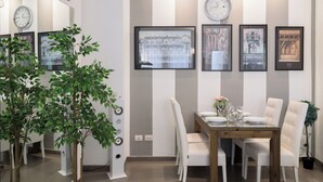 A dining area with a wooden table, white chairs, and framed pictures on the wall.