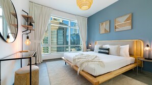 Ein modernes Schlafzimmer mit einem großen Bett, einem Nachttisch, einem Spiegel und einem Fenster mit Blick auf die Stadt.