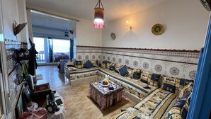 A living room with a sofa set, a coffee table, and a decorative wall. - Superb apartment in Targha, 100 m from the beach<br>15 km to oued law<br>5 km to karasras (Tétouan)
