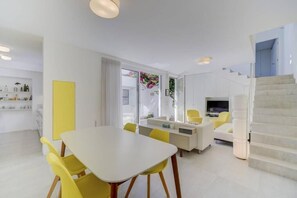 Ein modernes Wohnzimmer mit einem weißen Sofa, gelben Sesseln und einer Treppe.