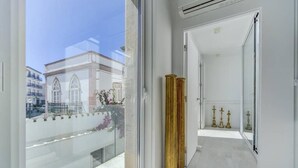 A modern hotel corridor with a glass balcony, a view of a building, and a row of golden columns. - Charming architect-designed house in the heart of Tavira (Tavira)