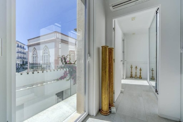 A modern hotel corridor with a glass balcony, a view of a building, and a row of golden columns. - A charming, architecturally designed house in the heart of Tavira (Tavira)