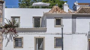 A white building with a tiled roof, a balcony, and a street lamp. - Charming architect-designed house in the heart of Tavira (Tavira)